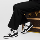 Model seated in black pants showcasing two-tone sneakers with athletic silhouette